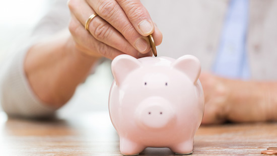 Close up of a woman dropping a coin into a piggy bank